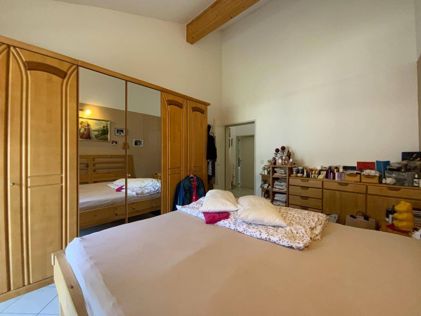 Schlafzimmer mit großem Holzdoppelbett, Spiegelschrank und Dachschräge.