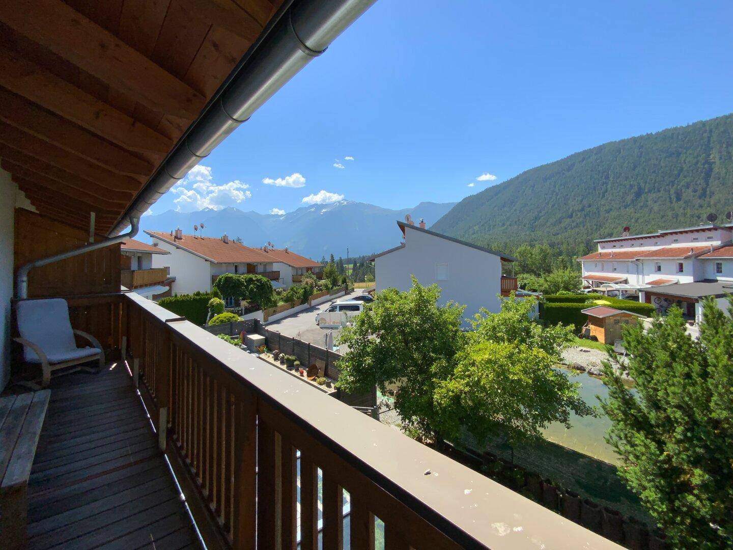 Geräumiger Balkon mit Holzboden und Geländer, bietet einen weiten Blick auf die umliegende Berglandschaft.