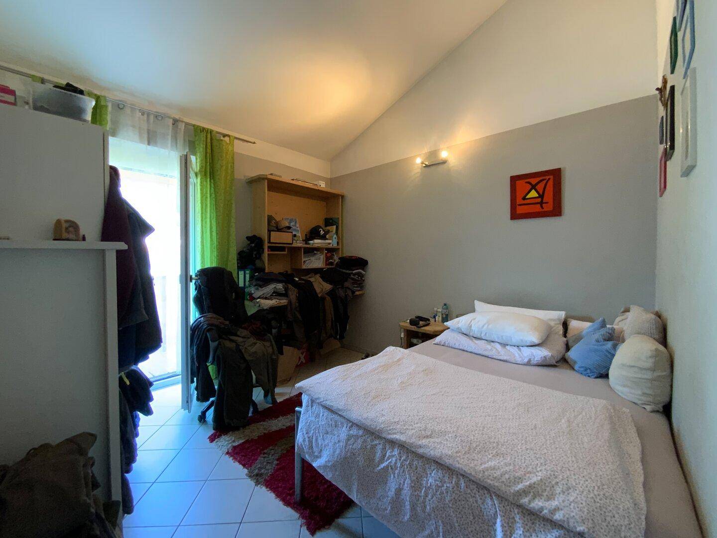 Schlafzimmer mit Arbeitsbereich, Zugang zum Außenbereich und schrägen Decken.