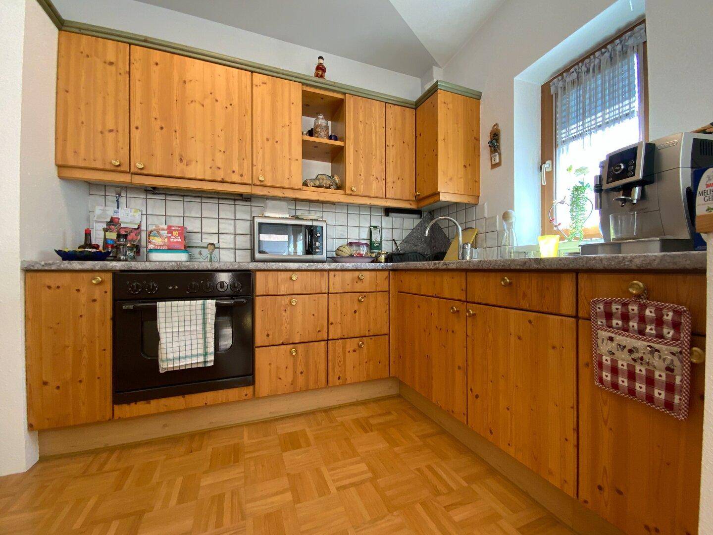 Detailansicht der Küche mit Holzfronten, integriertem Backofen und Mikrowelle.