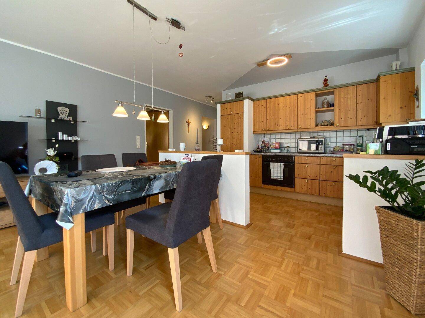 Gemütlicher Essbereich mit Holztisch und Stühlen, angrenzend an die Küche mit Holzfronten.