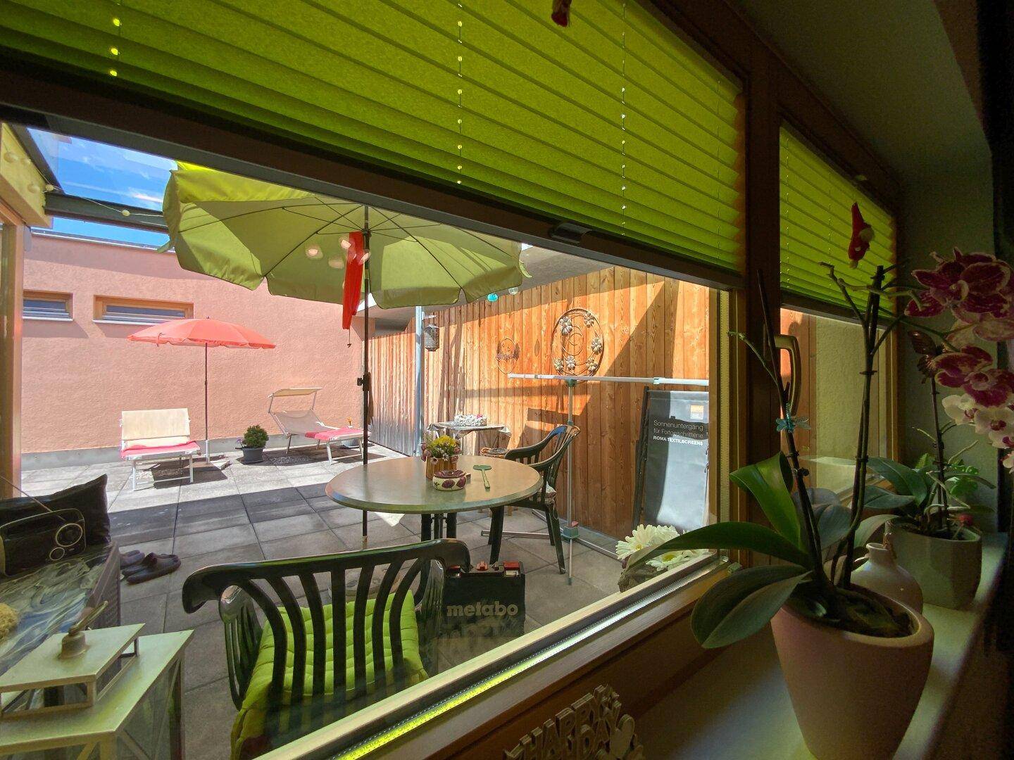 Fensterblick auf die private Terrasse mit Holzzaun und weiteren Sitzmöglichkeiten.