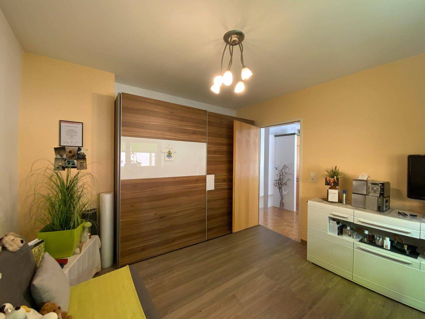 Schlafzimmer mit großem Einbauschrank und Zugang zu einem weiteren Raum.