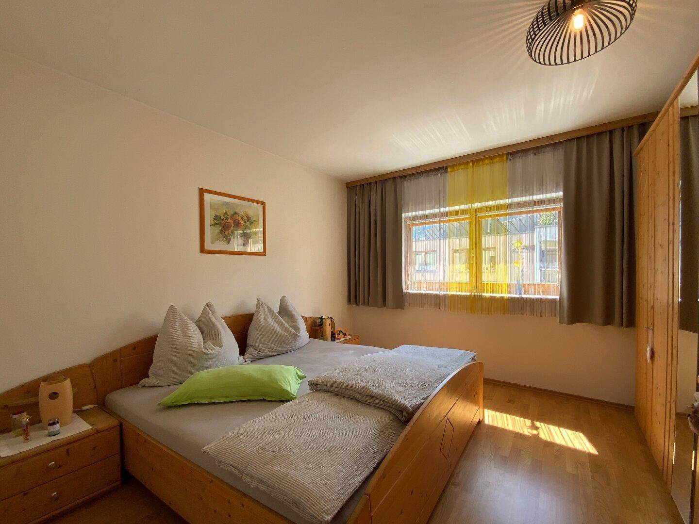 Gemütliches Schlafzimmer mit Holzbett, Nachttischen und Fenster für natürliches Licht.