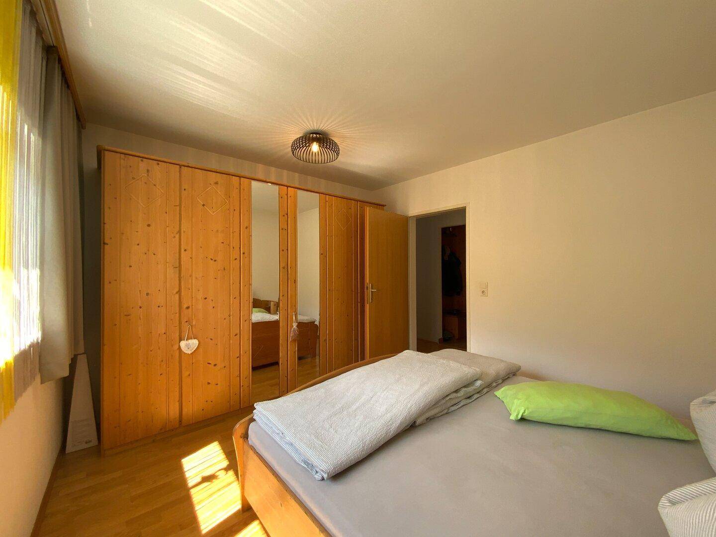 Schlafzimmer mit Holzbett und großem Kleiderschrank mit Spiegeltüren.