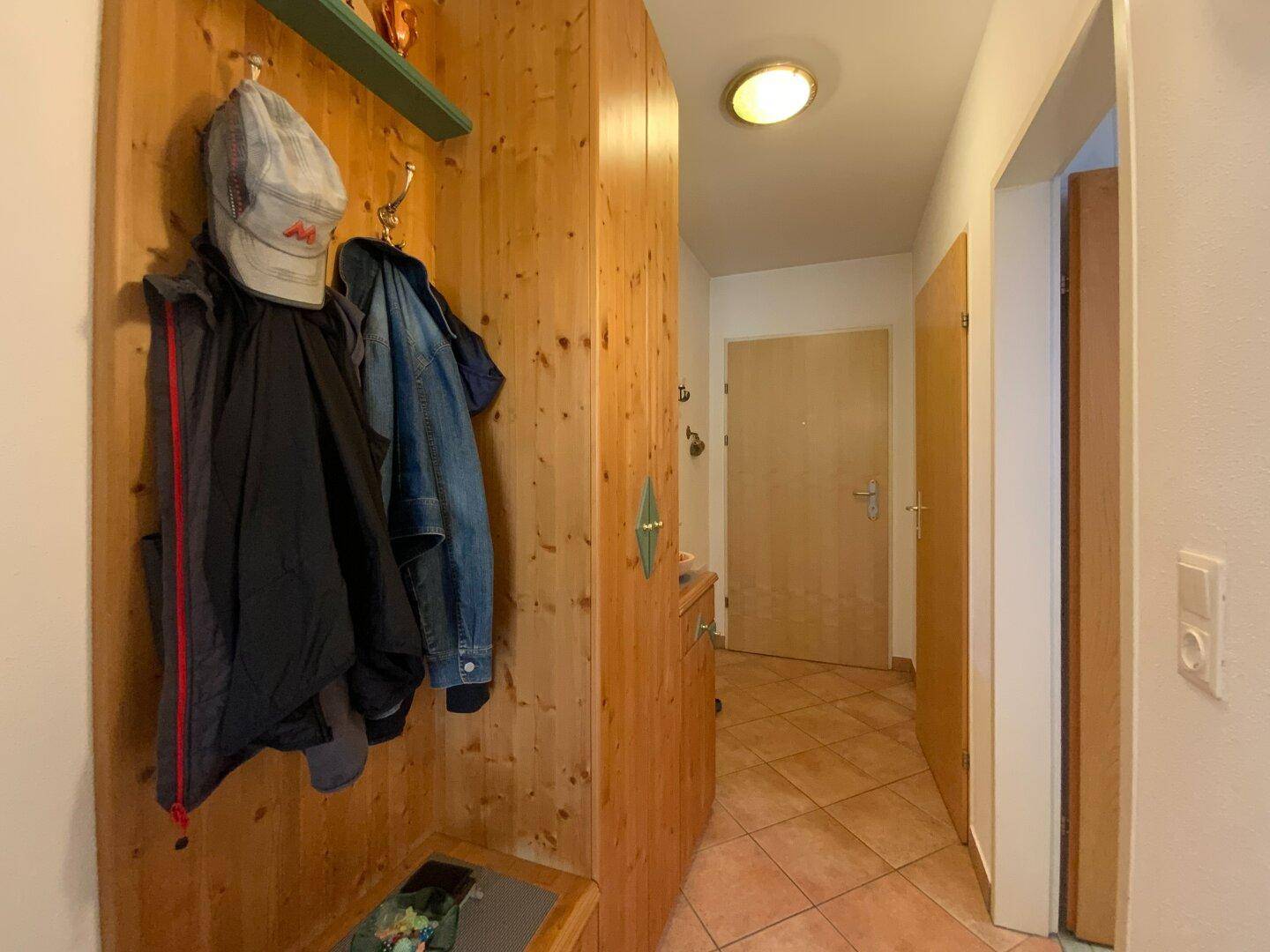 Eingangsbereich mit rustikaler Holzvertäfelung, Garderobe und Fliesenboden.