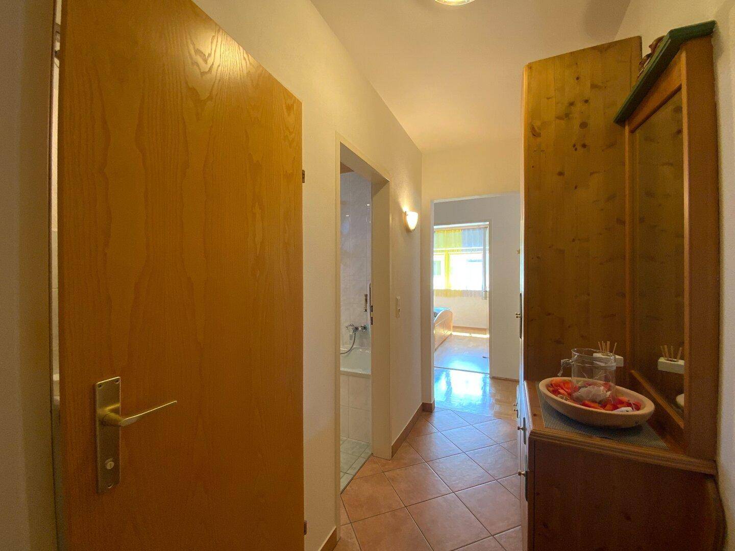 Heller Flur mit Fliesenboden, der zum Badezimmer und weiteren Räumen führt.