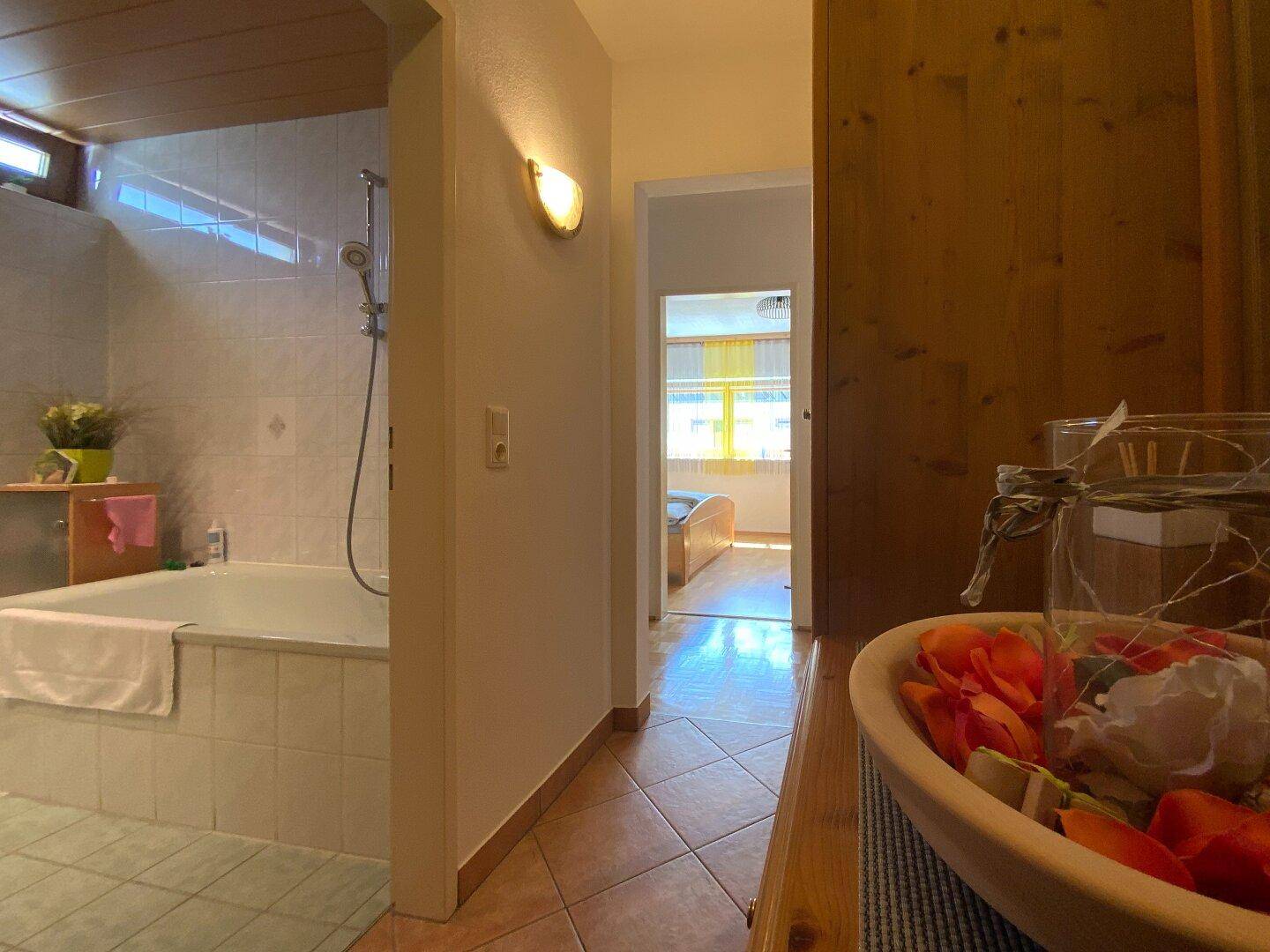 Flur mit Fliesenboden, der zu einem Badezimmer und einem weiteren Zimmer führt.