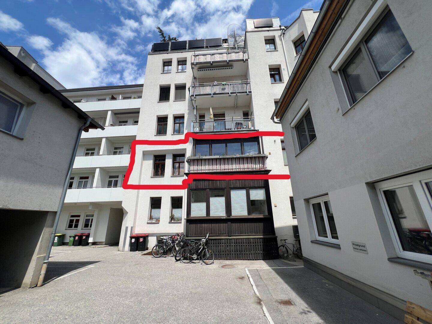 Rückansicht eines Wohngebäudes mit mehreren Balkonen und Fahrradabstellplätzen im Innenhof.