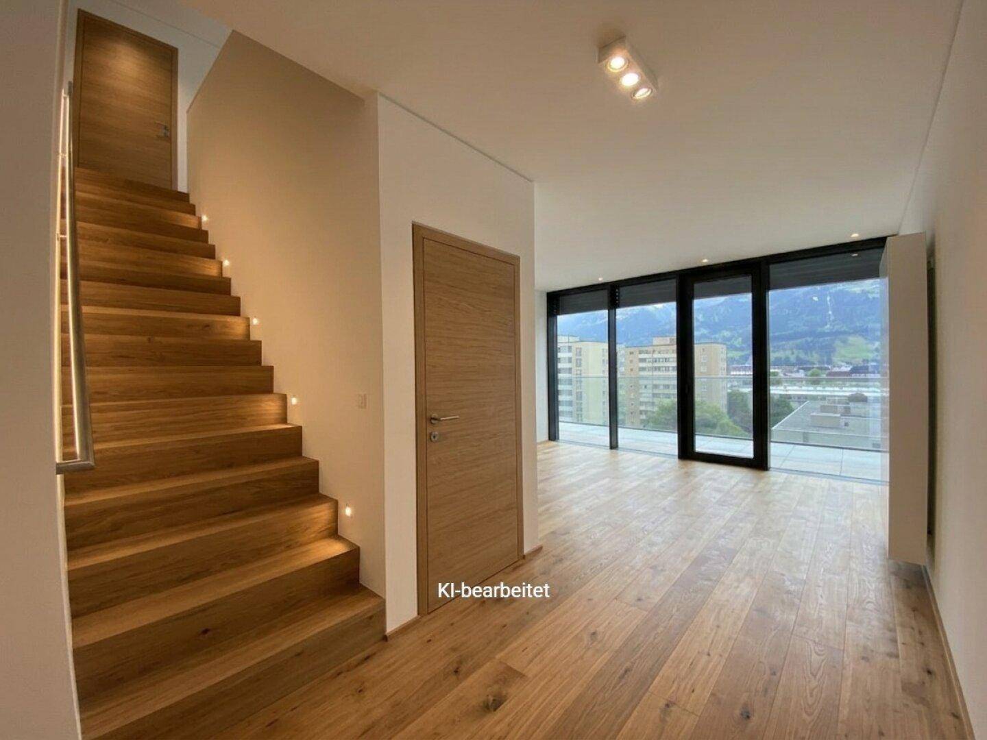 Heller Eingangsbereich mit eleganter Holztreppe, integrierter Beleuchtung und weitem Bergblick.