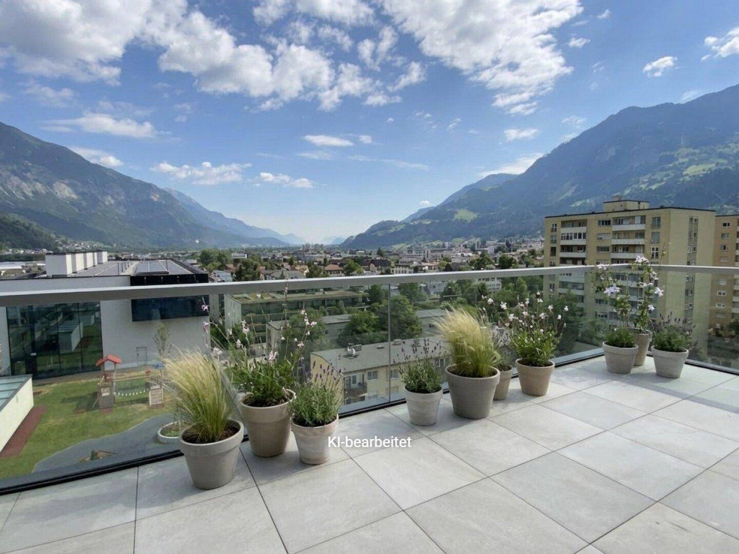 Geräumige Terrasse mit Pflanzen, Fliesenboden und weitem Blick auf die Berge und die Stadt.