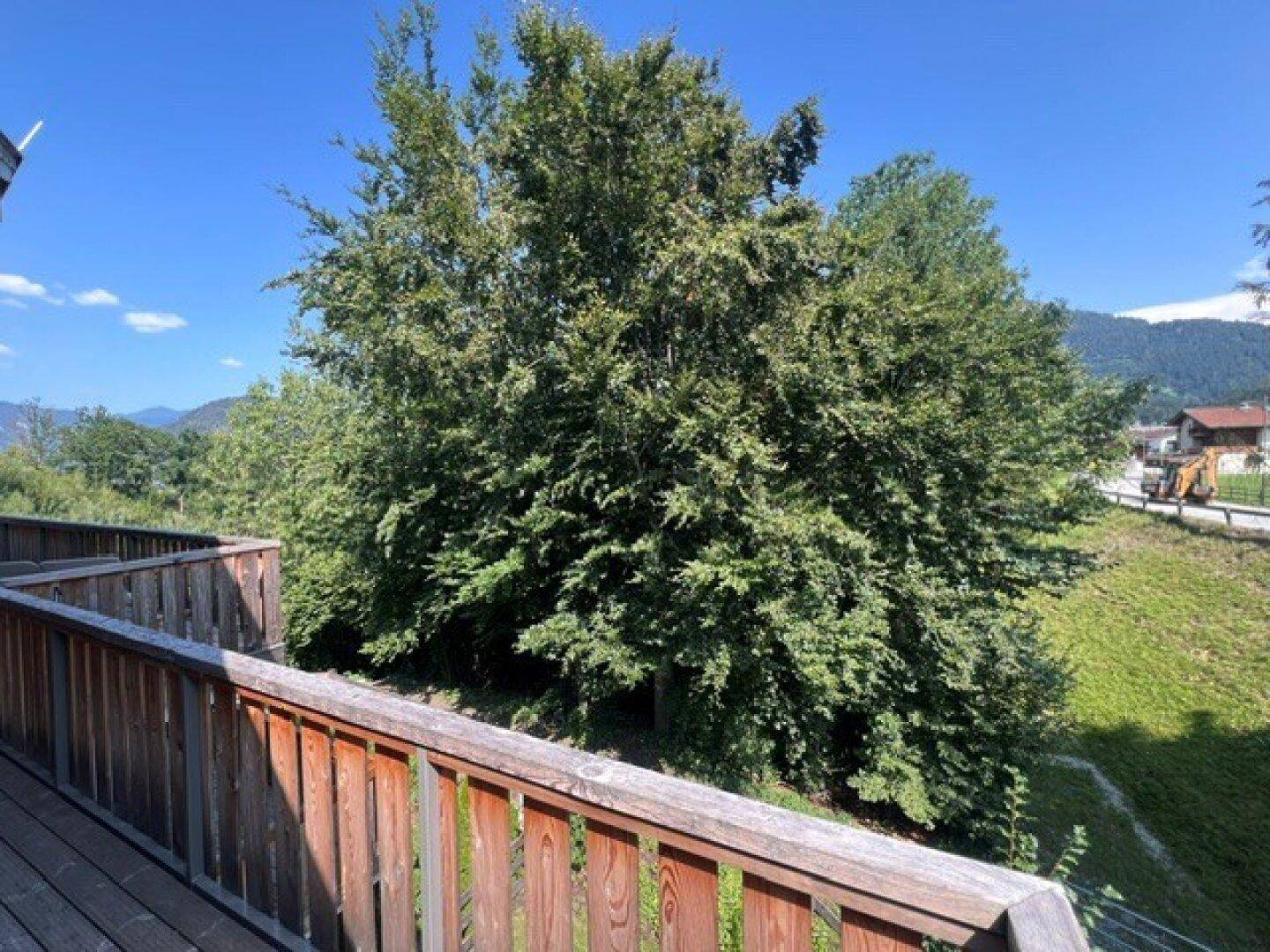 Blick vom Balkon auf üppige grüne Bäume und die umliegende Landschaft.