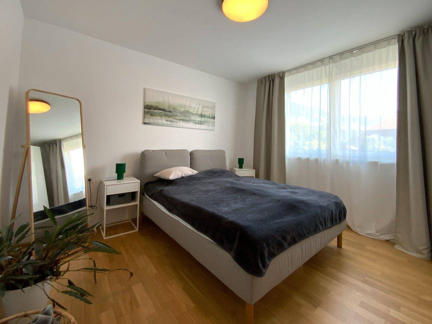 Gemütliches Schlafzimmer mit Doppelbett, Nachttischen und großem Fenster für viel Tageslicht.