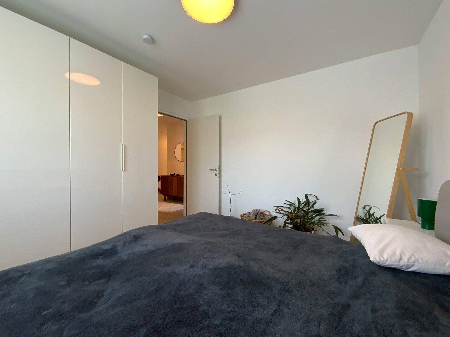 Schlafzimmer mit integriertem Kleiderschrank, Doppelbett und Zugang zum Flur.