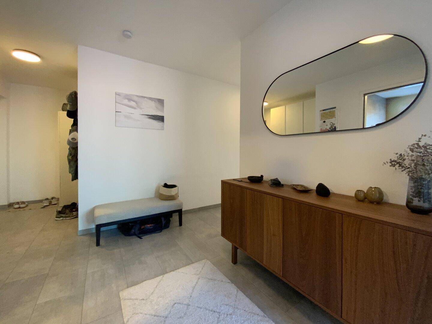 Eingangsbereich mit Fliesenboden, Garderobenbereich und modernem Sideboard.