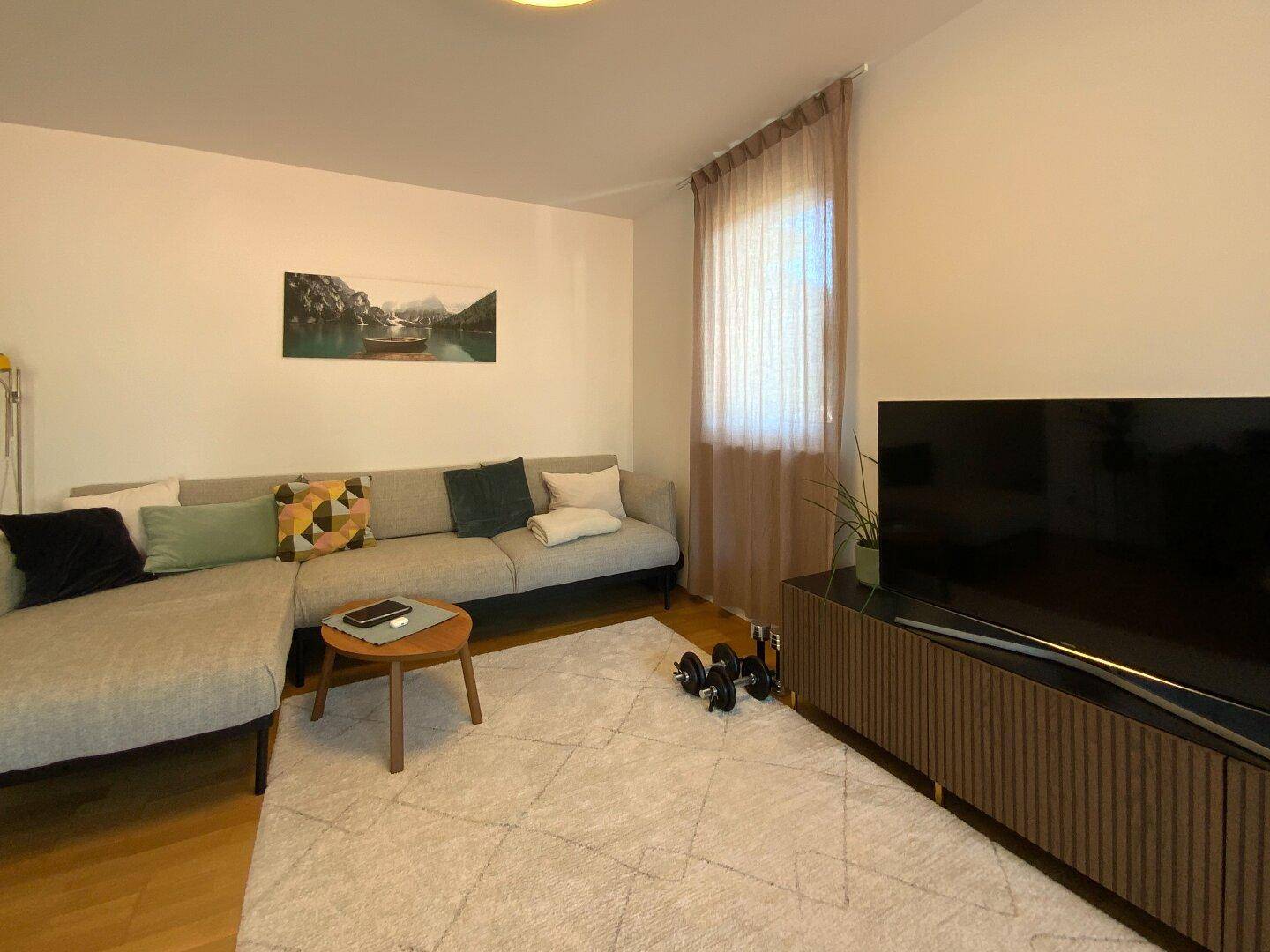 Helles Wohnzimmer mit großem Ecksofa, Teppich und modernem TV-Möbel.