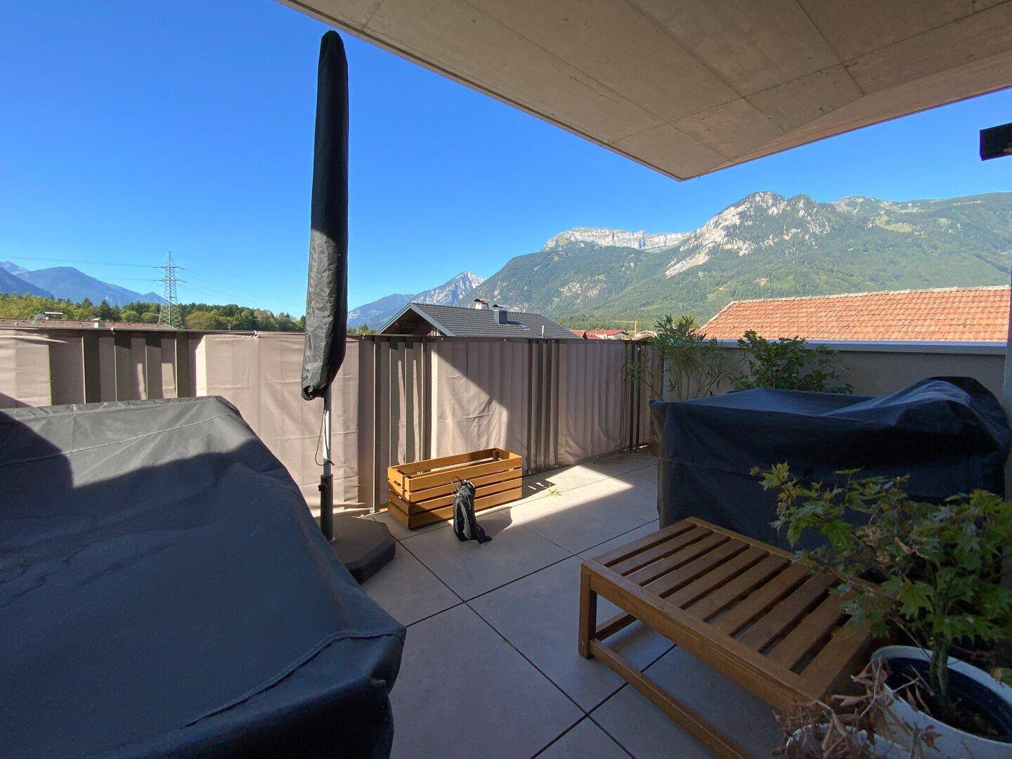Geräumige Terrasse mit überdachten Gartenmöbeln und beeindruckendem Bergblick.