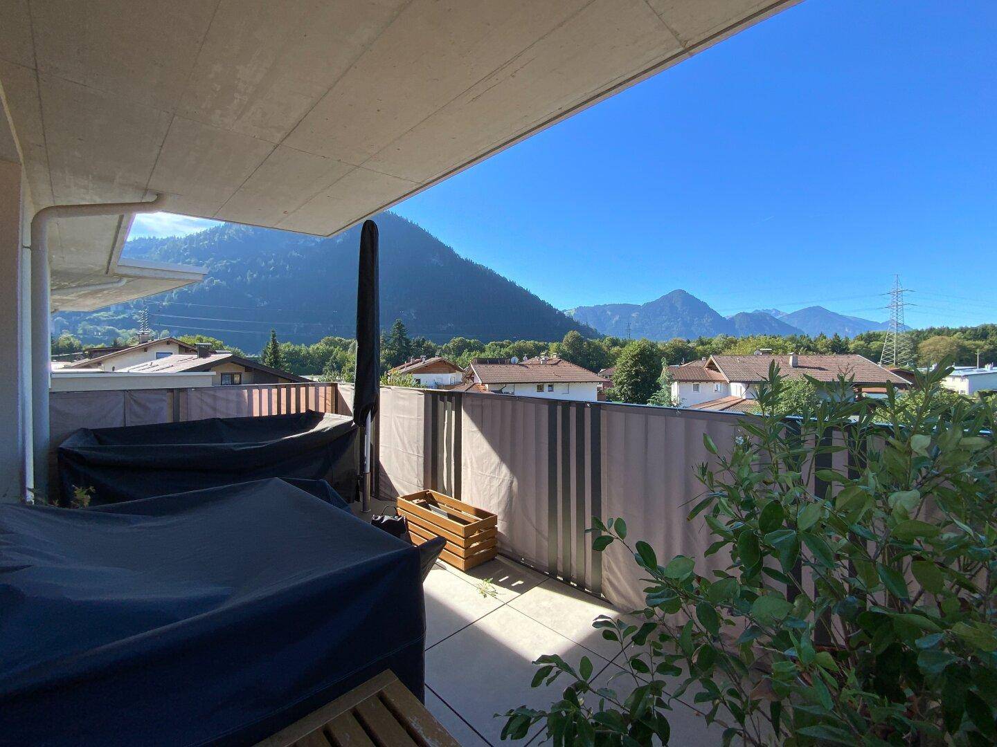 Überdachte Terrasse mit Bergblick, geschütztem Sitzbereich und Pflanzen.