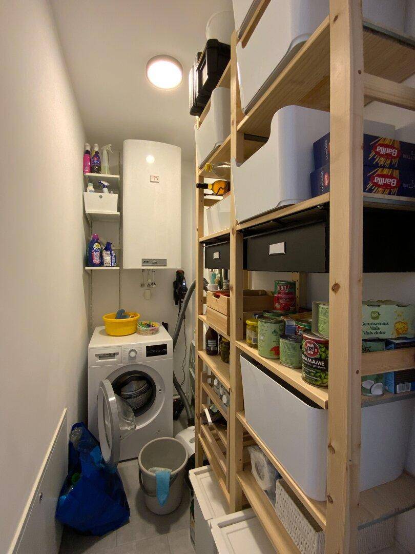 Praktischer Hauswirtschaftsraum mit Waschmaschine, Warmwasserbereiter und Holzregalen für Stauraum.