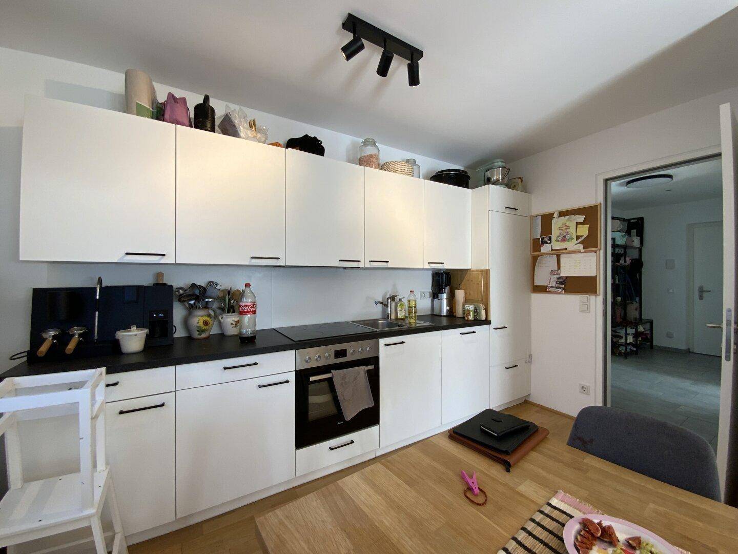Moderne Küche mit weißen Schränken, dunkler Arbeitsplatte und Holzboden.