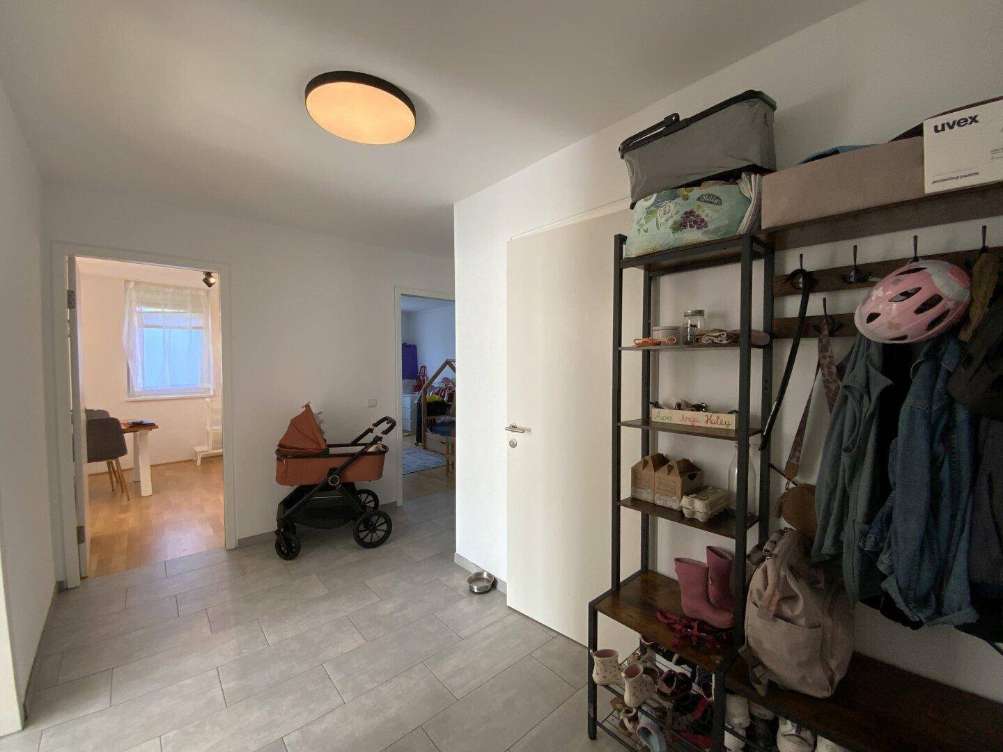 Heller Flur mit Fliesenboden, Garderobe und Zugang zu weiteren Räumen.