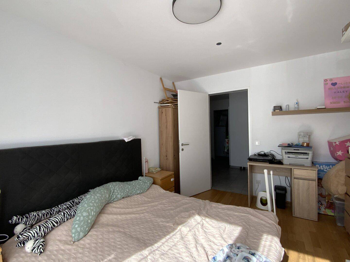 Schlafzimmer mit Holzboden, großem Bett und Schreibtisch.