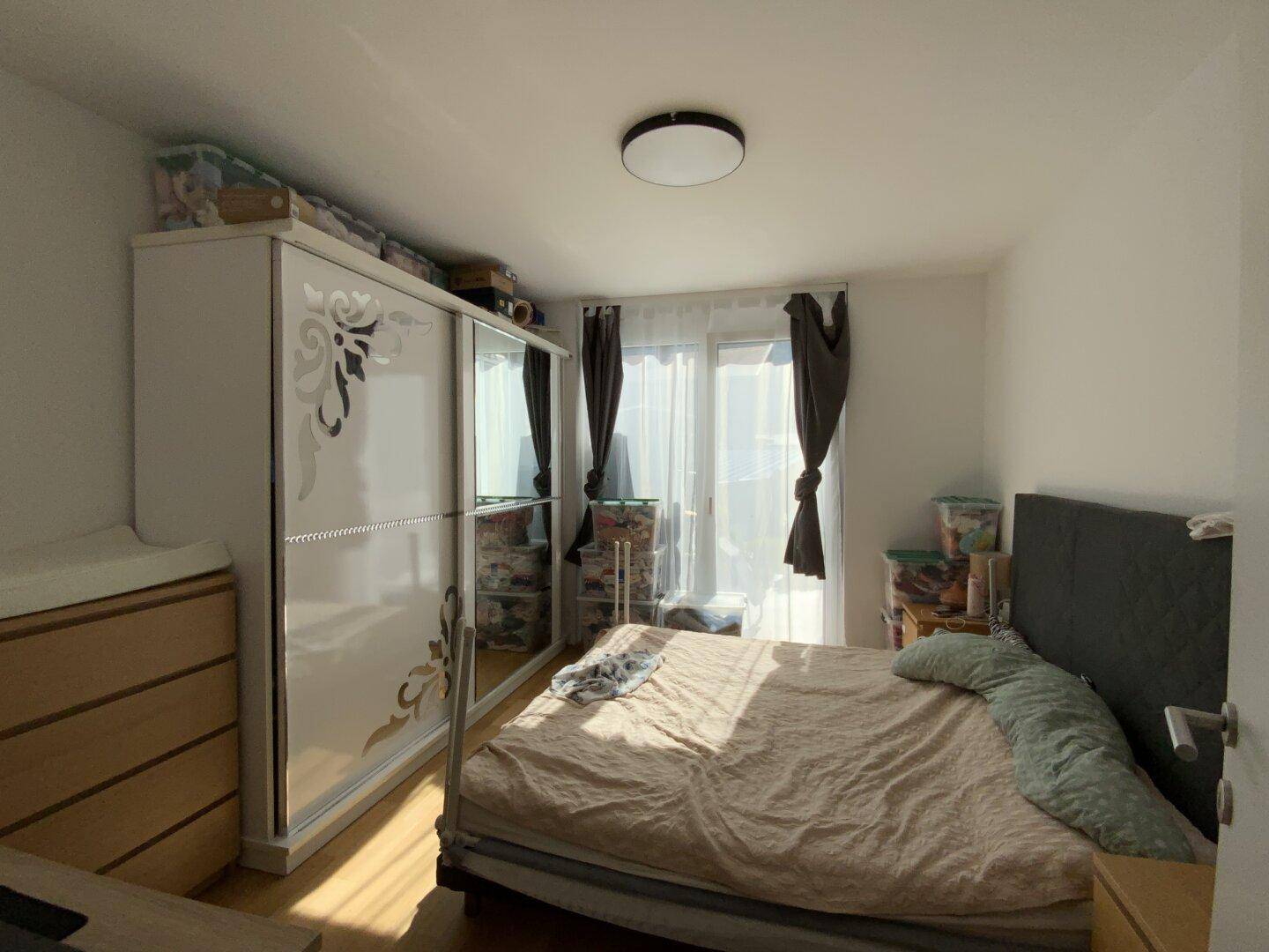 Helles Schlafzimmer mit großem Kleiderschrank, Doppelbett und Zugang zum Balkon.