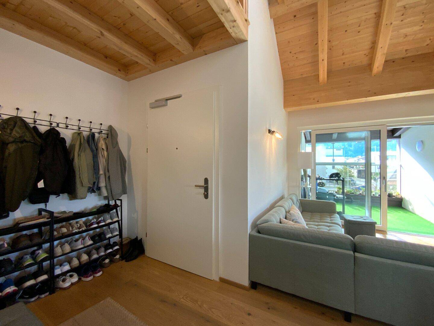 Heller Eingangsbereich mit Garderobe und direktem Zugang zum Wohnbereich mit Terrasse.