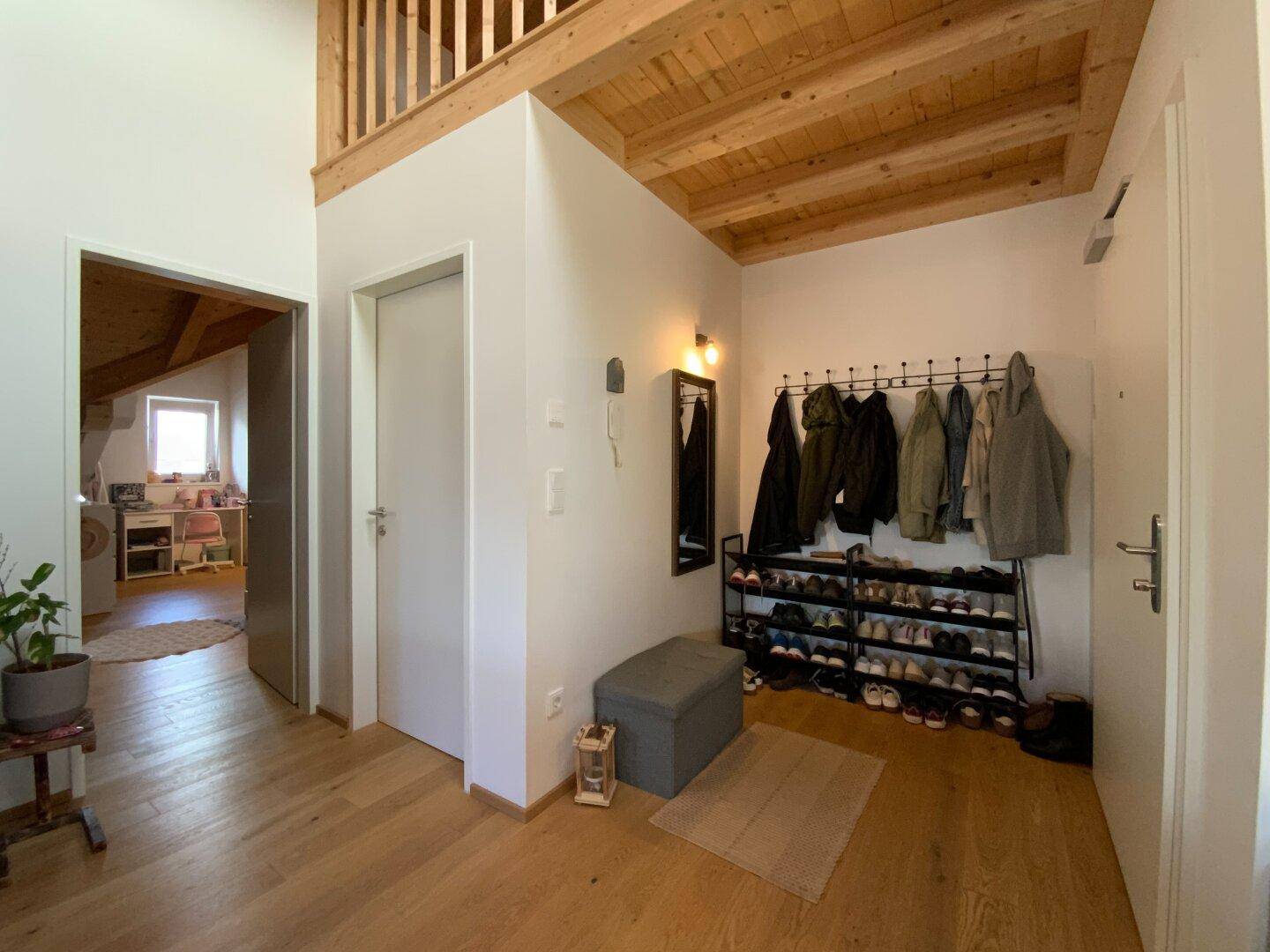 Eingangsbereich mit Garderobe, Schuhregal und Blick in den offenen Wohnbereich.