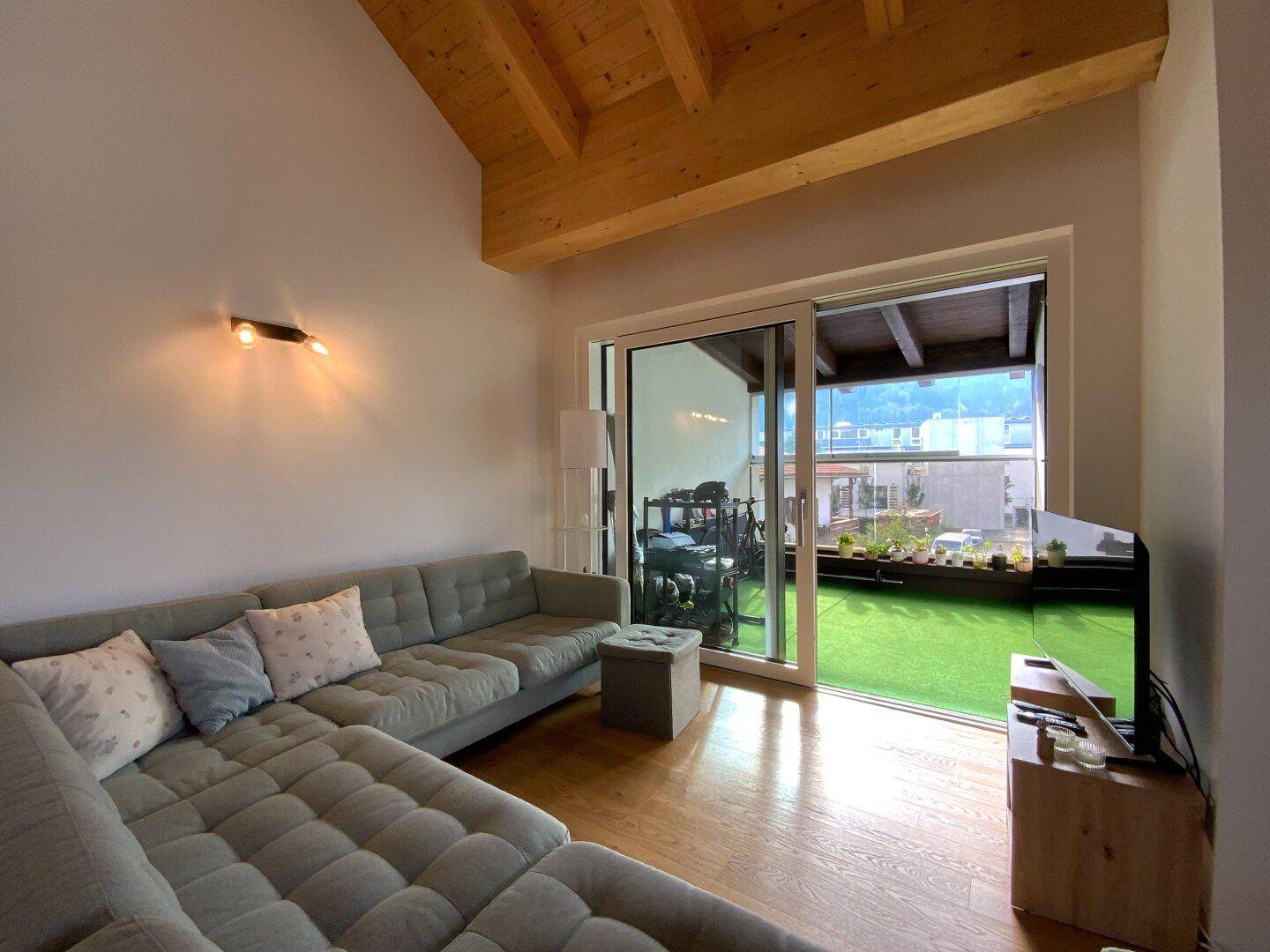 Gemütlicher Wohnbereich mit großem Ecksofa und Schiebetür zur begrünten Terrasse.