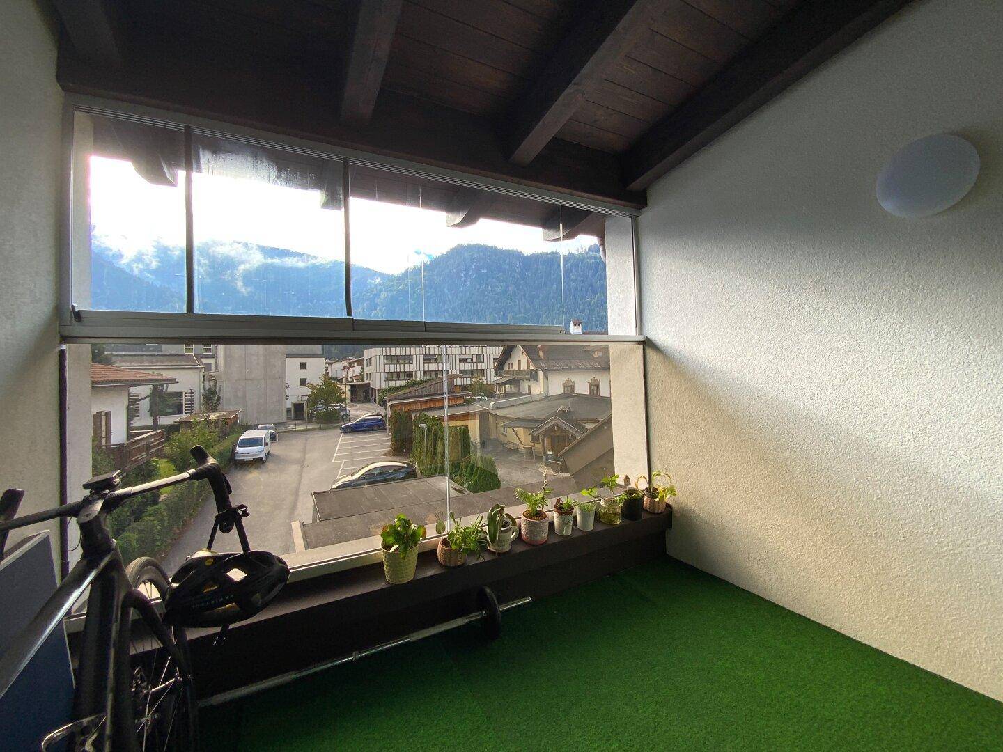 Verglaste Loggia mit Panoramablick auf die Berge und die umliegende Bebauung.