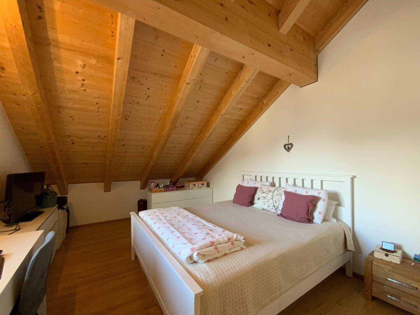 Geräumiges Schlafzimmer mit Doppelbett, Holzbalkendecke und Dachschräge.