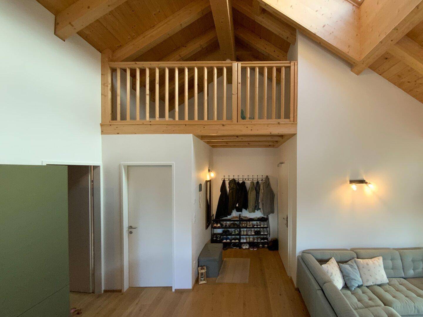 Eingangsbereich mit Garderobe und Blick auf die Holzgalerie und die hohen Decken.