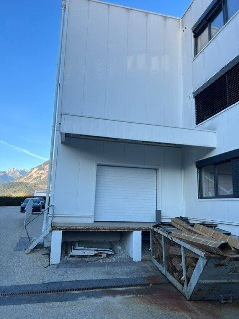 Laderampe eines modernen Geschäftsgebäudes mit Rolltor und Blick auf die umliegenden Berge.