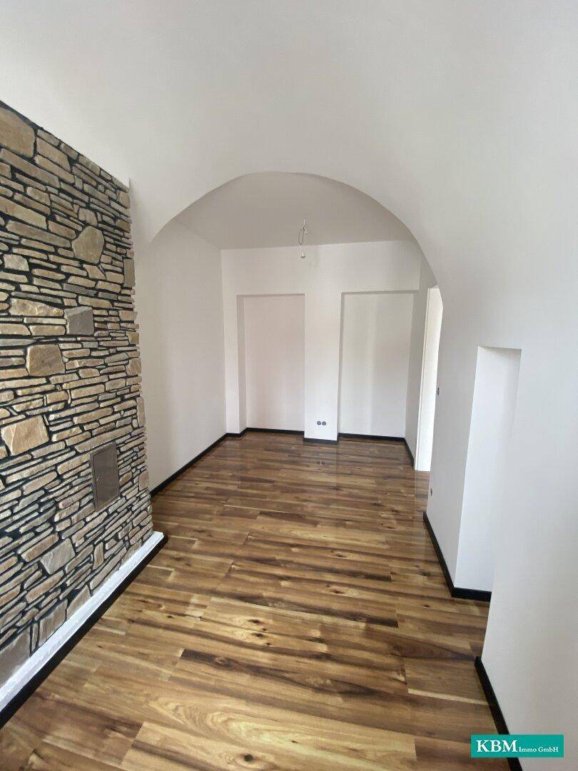 Flur oder Raum mit Gewölbedecke, Holzboden und dekorativer Steinwand, die historischen Charme versprüht.
