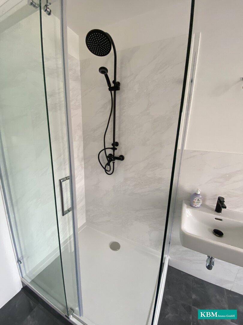 Detailansicht der modernen Duschkabine mit Regenduschkopf und minimalistischem Design für Entspannung.