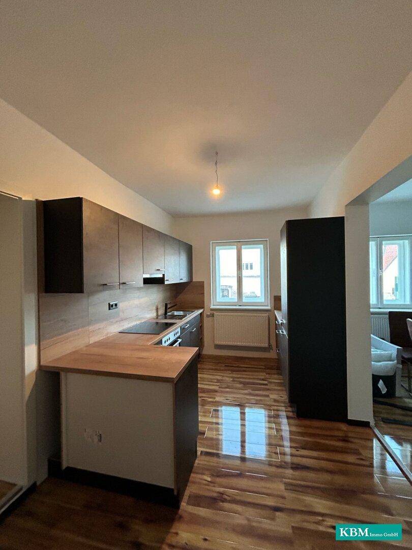 Geräumige Küche mit dunklen Schränken, Holzarbeitsplatte und Fenster für angenehmes Tageslicht.