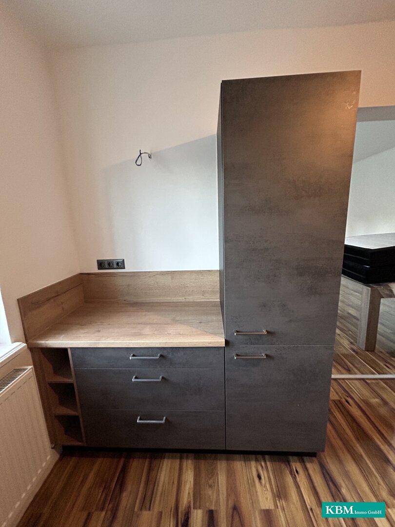 Detailansicht der modernen Küchenzeile mit dunklen Schränken und Holzdetails, funktional und stilvoll.