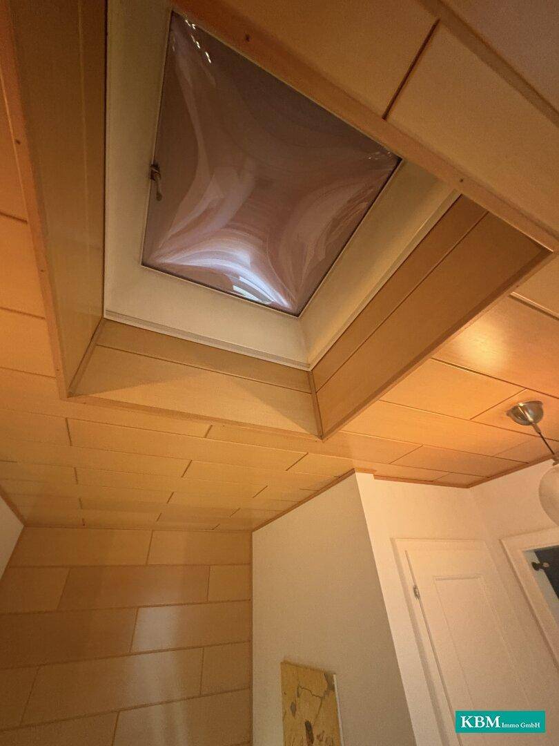 Decke mit Holzverkleidung und integriertem Dachfenster für natürliches Licht.