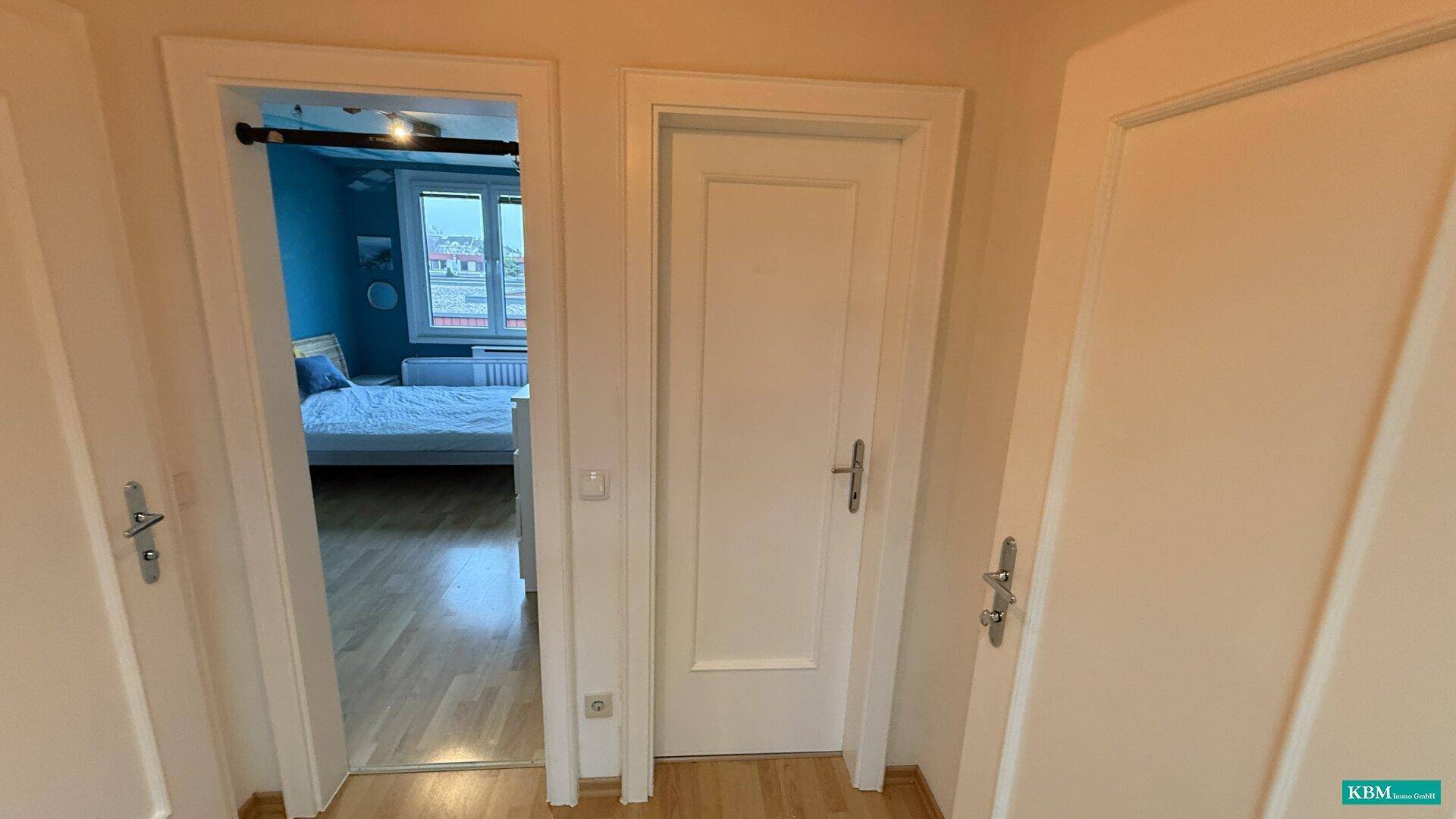 Flur mit weißen Türen und Blick in ein angrenzendes Schlafzimmer.