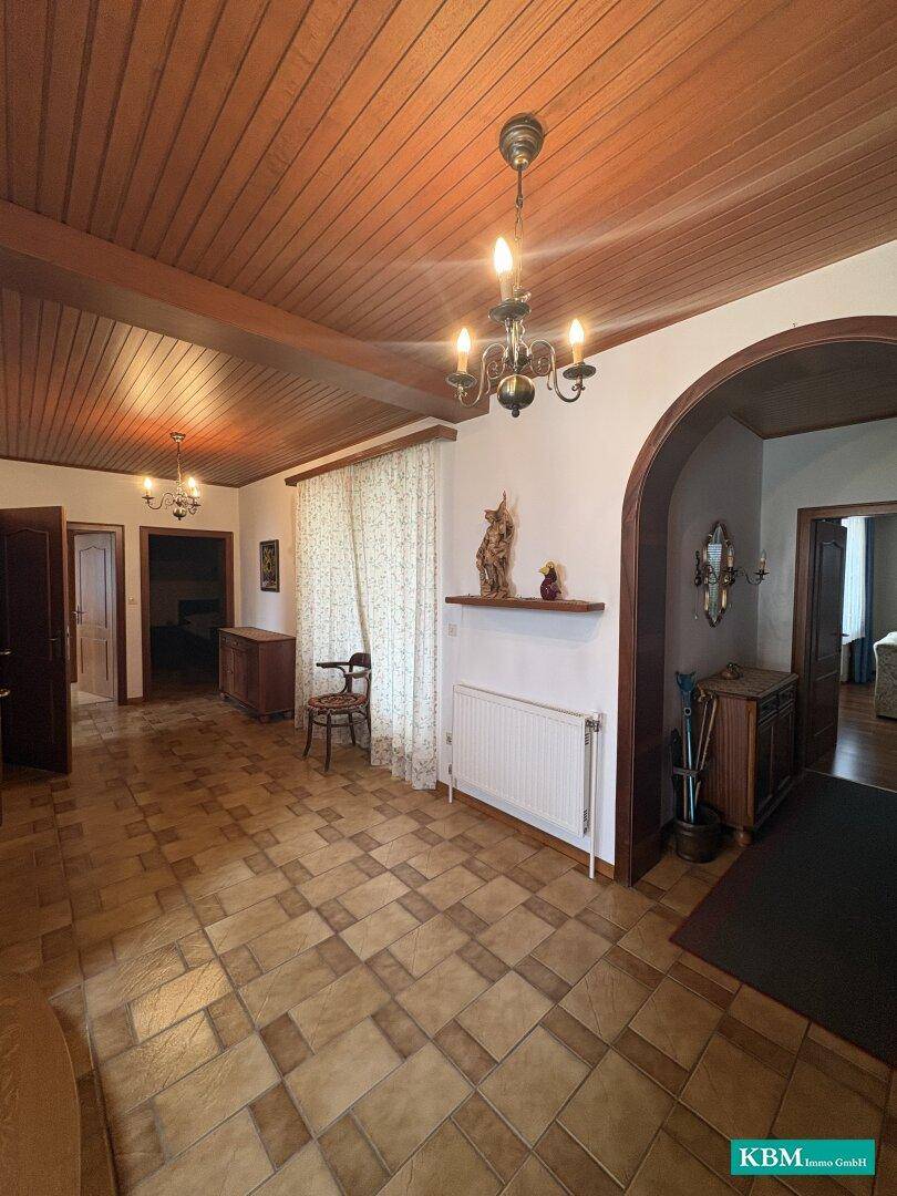 Geräumiger Flur mit Holzdecke, Fliesenboden und dekorativen Elementen.
