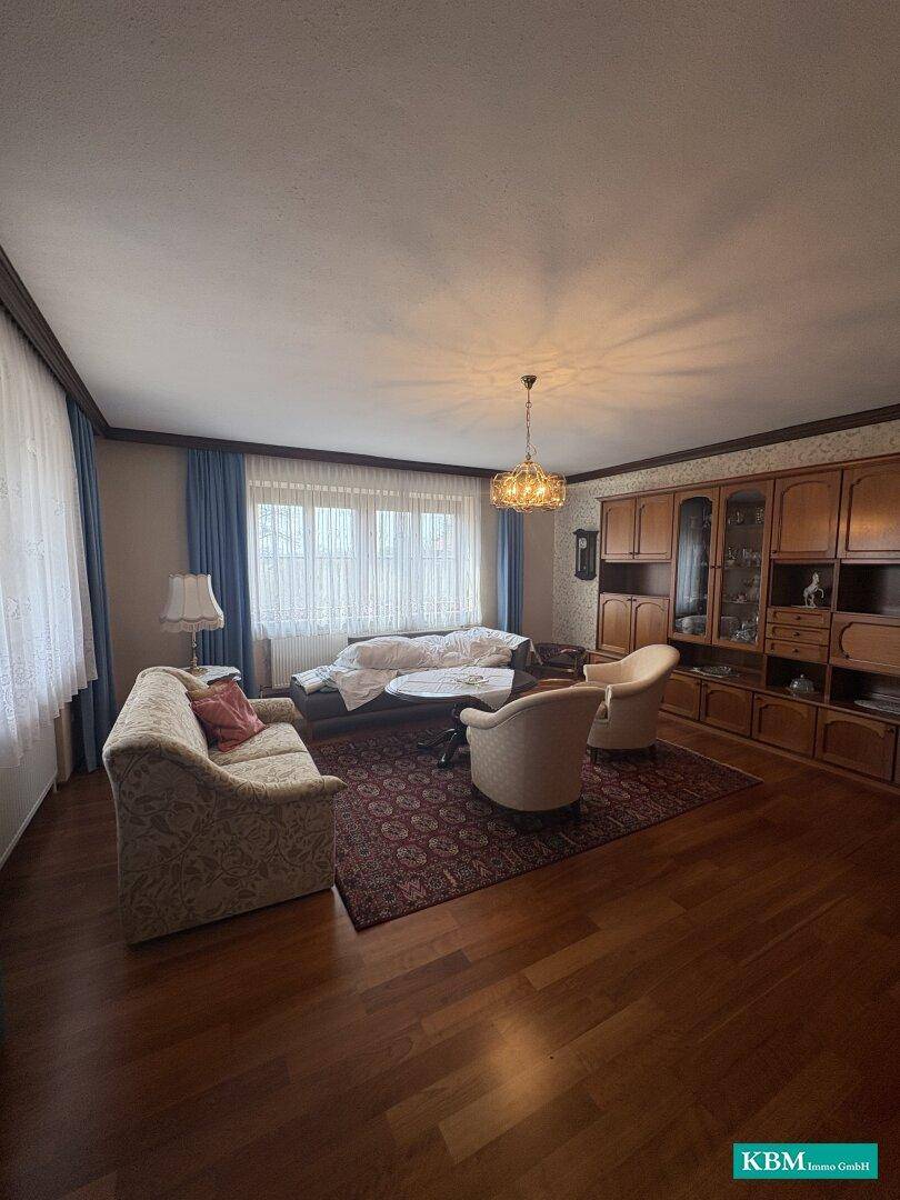 Geräumiges Wohnzimmer mit Holzschrankwand, Teppich und Parkettboden.