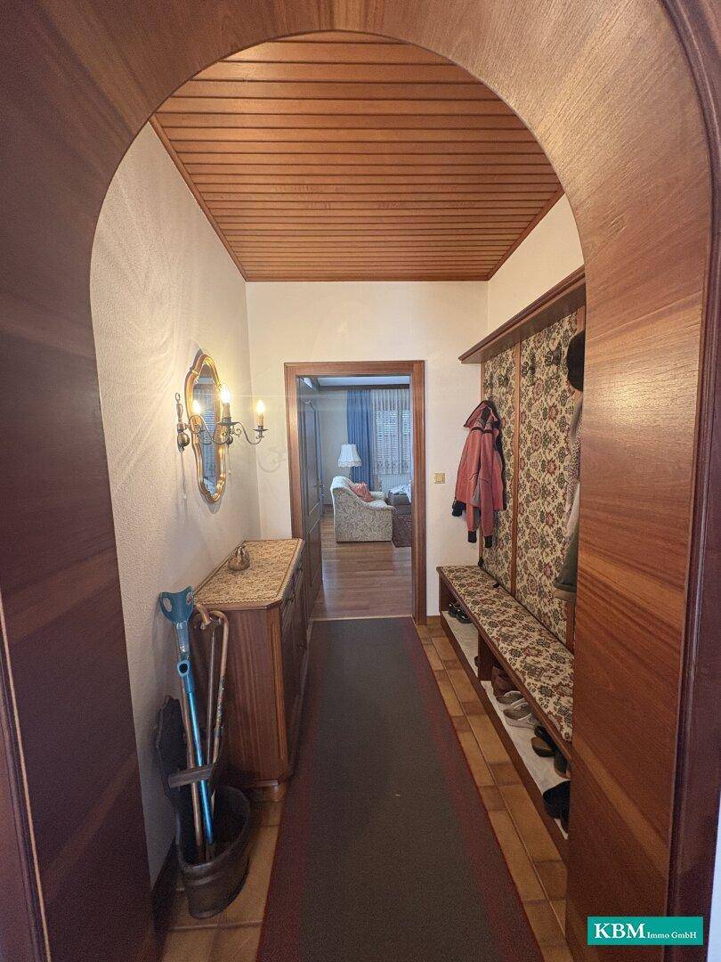 Eingangsbereich mit Holzdecke, Fliesenboden und Garderobe, führt in den Wohnbereich.