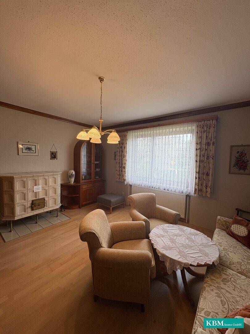 Gemütliches Wohnzimmer mit Kachelofen, Parkettboden und traditionellen Möbeln.