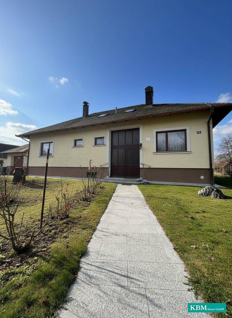 Vorderansicht des Hauses mit gepflegtem Rasen und einem Weg zum Eingang.