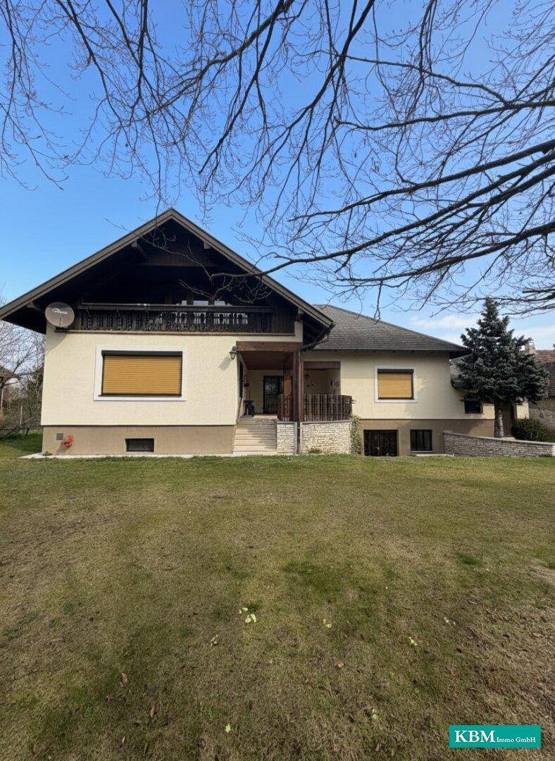 Rückansicht des Hauses mit großem Garten und überdachtem Eingangsbereich.