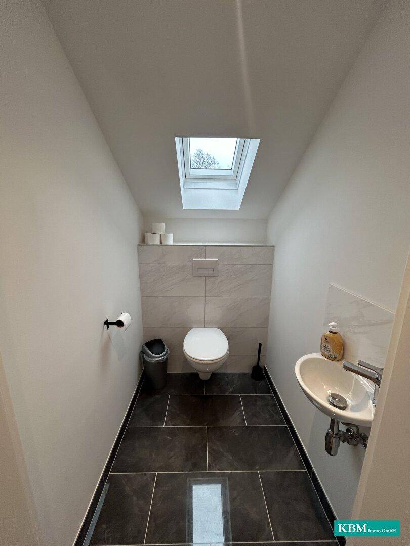 Kleines Gäste-WC mit modernem Design, Hänge-WC und Dachfenster für natürliches Licht.