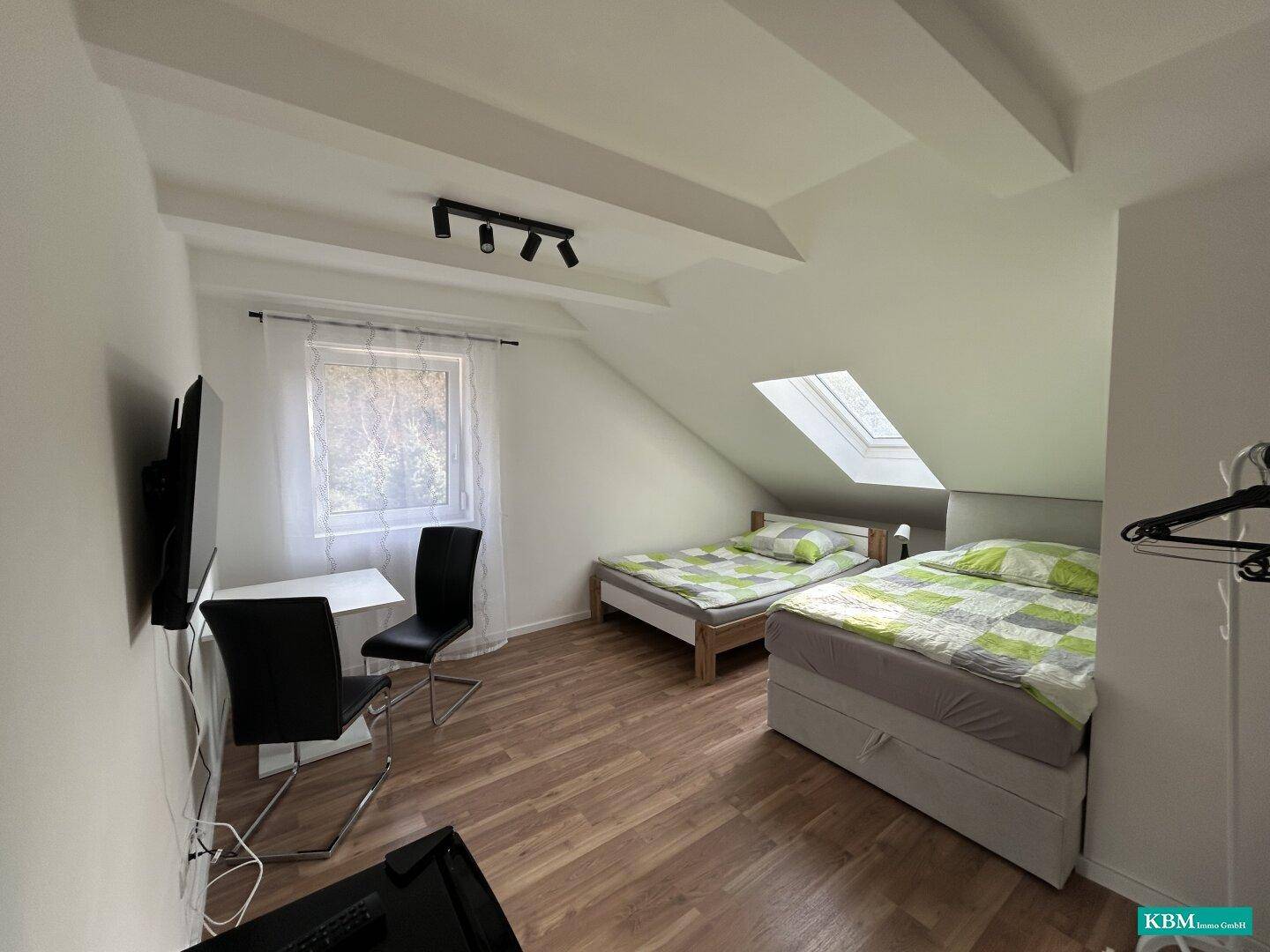 Gemütliches Schlafzimmer im Dachgeschoss mit zwei Betten, Dachschräge und Dachfenster.