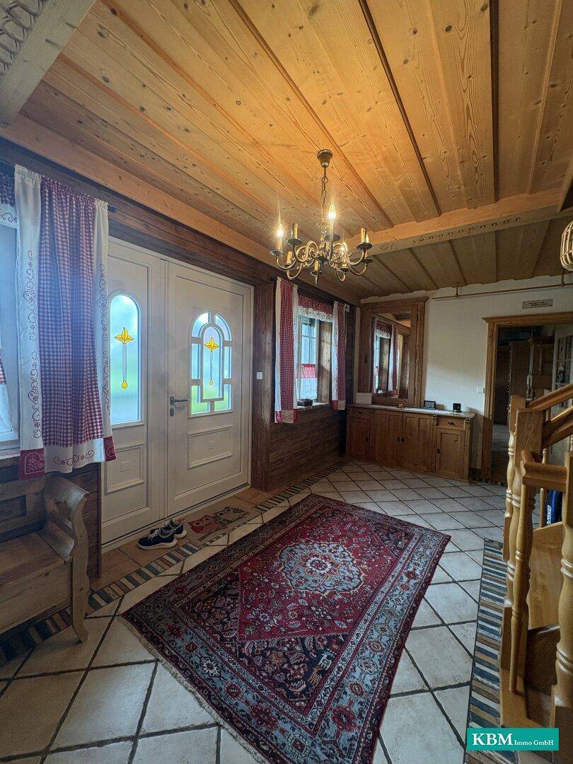 Einladender Eingangsbereich mit Holztür, Kachelboden und traditionellem Kronleuchter.