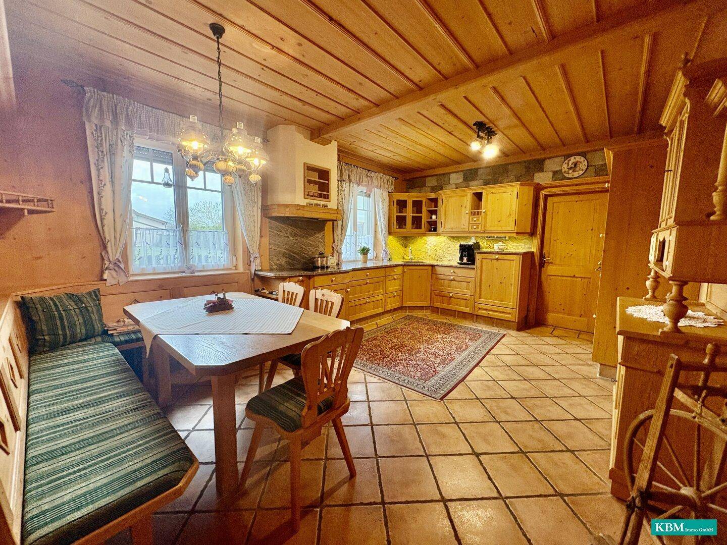 Rustikale Wohnküche mit Holzeinbauten, Kachelboden, Essecke und traditionellem Flair.